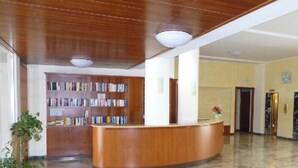 Ein Empfangsbereich mit einem Holzbüro, einem Bücherregal und zwei Aufzügen.