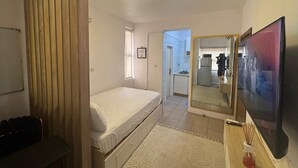 A bedroom with a bed, a desk, a mirror, and a TV. - Cozy 1-bedroom apartment in peaceful Lagos with AC, gym and pool access (Lagos)