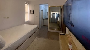 A bedroom with a single bed, a TV, and a mirror. - Cozy 1-bedroom apartment in peaceful Lagos with AC, gym and pool access (Lagos)