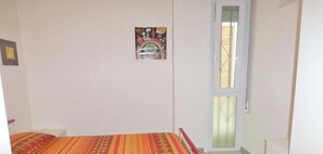 A bedroom with a bed, a small window, and a wall decoration. - Apartment 'Vera Cruz 106' with Shared Pool and Private Terrace (Lido di Jesolo)