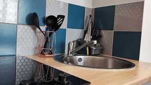 A kitchen with a stainless steel sink, a black induction cooktop, and a copper utensil holder. - Montesquieu: Splendid and charming studio (Roubaix)