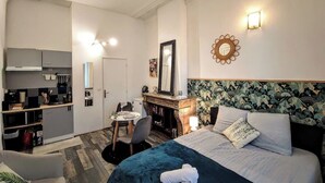 A hotel room with a bed, a desk, a chair, a wardrobe, and a mirror. - Montesquieu: Splendid and charming studio (Roubaix)