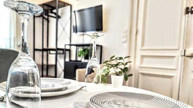 A dining table set with plates, a wine glass, and cutlery. - Montesquieu: Splendid and charming studio (Roubaix)