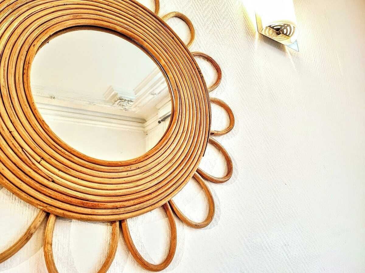 A circular mirror with a sun-like design on a white wall.