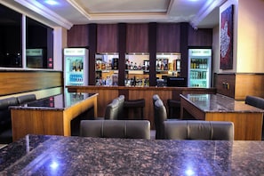 A bar area with seating, a counter, and a refrigerator labeled 'RESTP INT'. - Grand Commodores Hotel And Suites (Oyo)