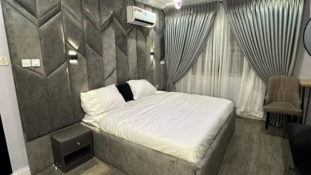 Ein modernes Schlafzimmer mit einem großen Bett, einem Nachttisch, einem Sessel und einem Schreibtisch.