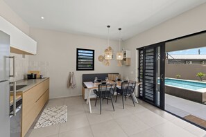 A modern kitchen with a dining area, a pool, and a sliding glass door to the outside. - Villa Anosia Laman: View with sunset, private pool, and 2 beaches nearby (Westpunt)