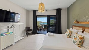 Ett hotellrum med en säng, en TV, ett skrivbord och en balkong med utsikt.