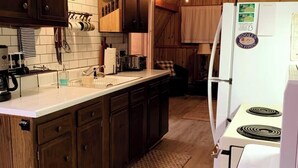 Une cuisine avec des meubles de rangement en bois, un plan de travail blanc, une cuisinière et un réfrigérateur.