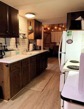 A kitchen with wooden cabinets, a white countertop, a stove, and a refrigerator. - Secluded A-frame Loft Cabin on Lincoln Hills Trails Firepit ATV Friendly! (Irons)
