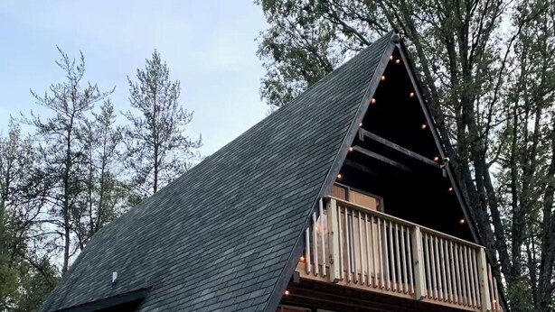 Une cabane dotée d’un toit en pente, d’un balcon et d’une porte donnant sur l’intérieur.