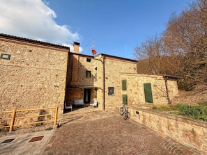 Un edificio de piedra con un patio, una bicicleta y un veleta.