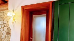 Une porte en bois avec un panneau de verre, un mur en pierre et un luminaire fixé au mur.