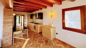 Une cuisine avec des poutres en bois, un parquet en point de Hongrie, une fenêtre et un évier.
