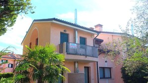 Un edificio de dos plantas con un balcón, una chimenea y un cartel que indica que está en venta.