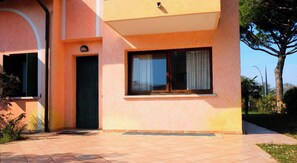 A building with a flat facade, a door, and a window with curtains.
