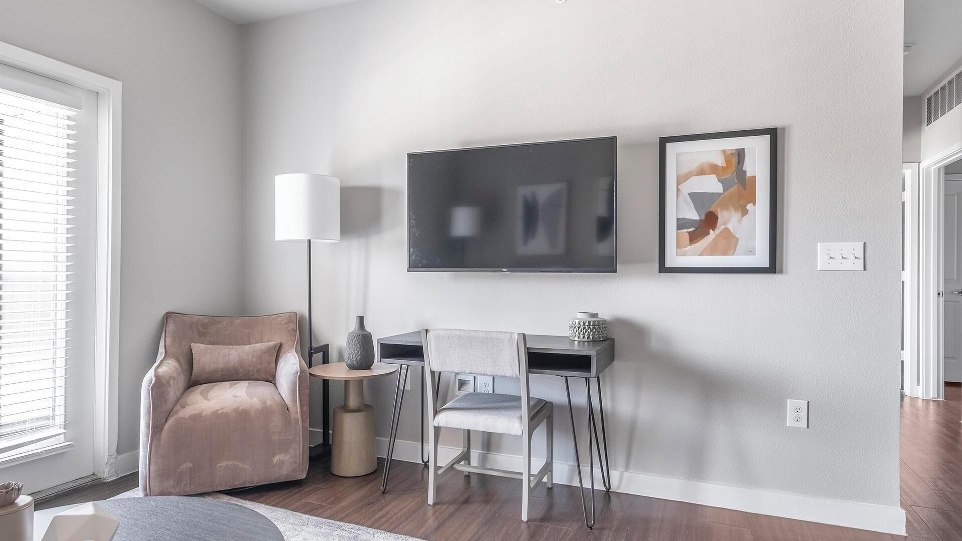 Un salon moderne avec un téléviseur à écran plat, un canapé, une table basse et un fauteuil.