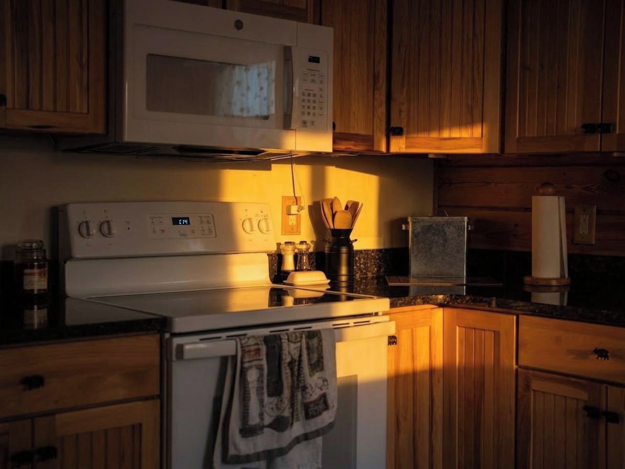 A kitchen with wooden cabinets, a microwave, a stove, and a sink.