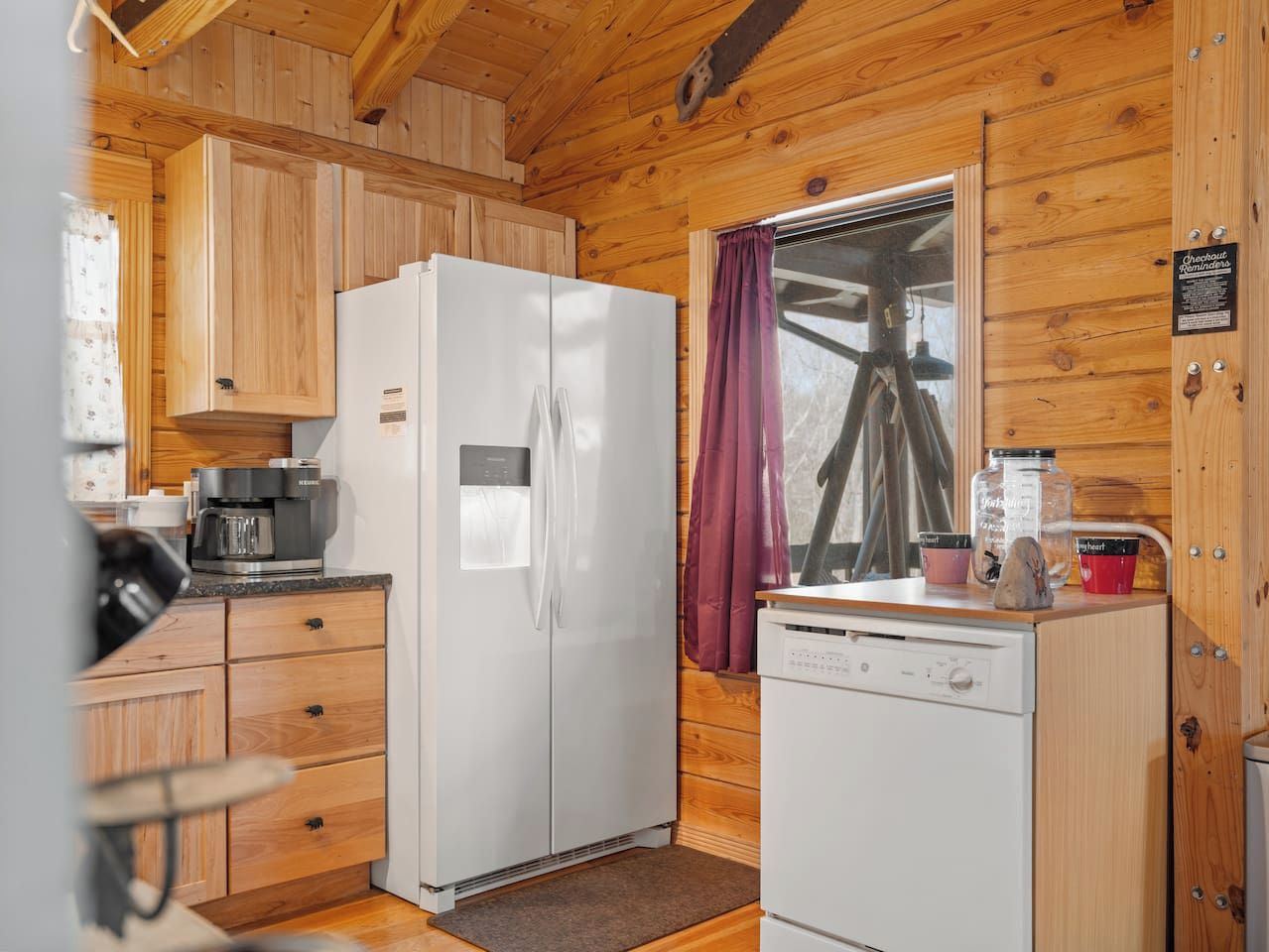 A compact kitchen with wooden cabinets, a refrigerator, a coffee maker, and a dishwasher.