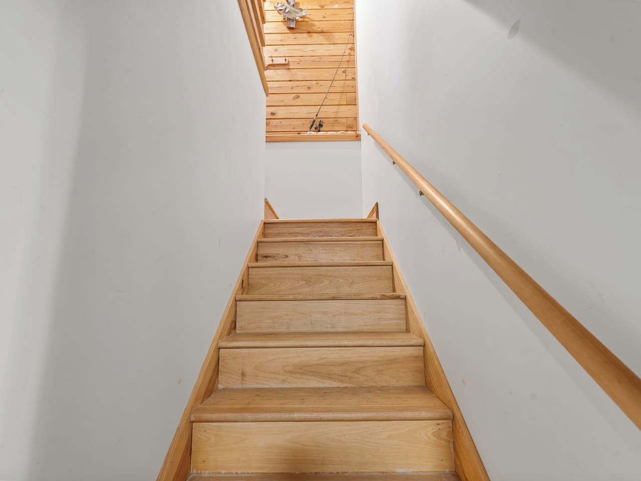 A wooden staircase with a handrail, leading to a higher floor.