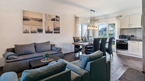 Una sala de estar moderna con sofá, mesa de centro y comedor con sillas y una mesa.