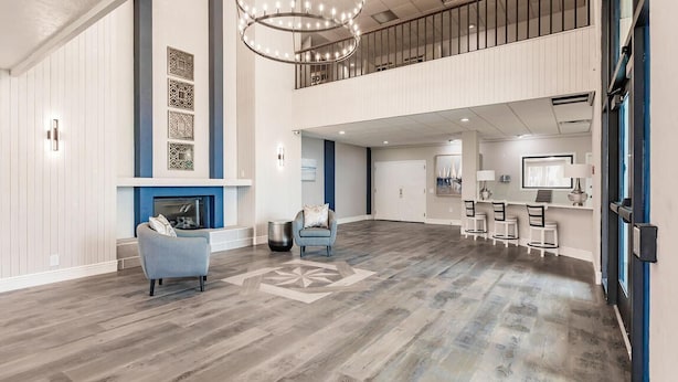 A spacious lobby with a fireplace, seating area, and a dining setup. - Landing Apartments Near HCA Florida Fawcett Hospital (Port Charlotte)