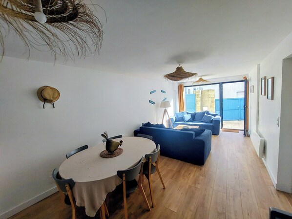A room with a dining table, a sofa, and a view of the outside. - Carnac City Center, 4-bedroom house, 3 bathrooms – sleeps 8. Beaches & Walking Routes (Carnac)