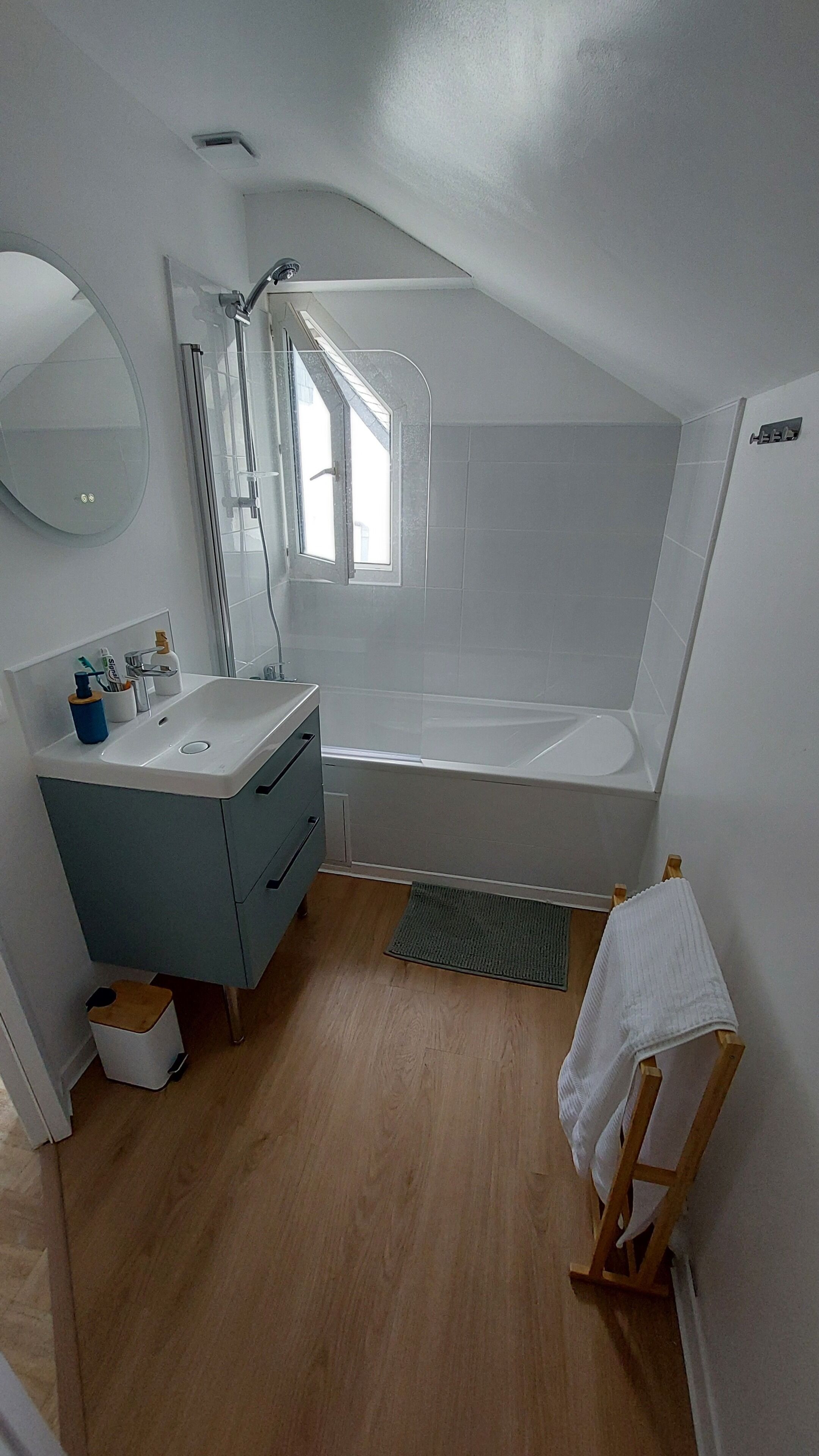 A small, modern bathroom with a sink, mirror, and shower.