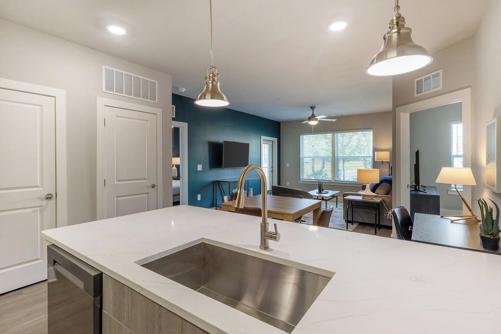 A modern kitchen with a central island, stainless steel sink, and pendant lighting.