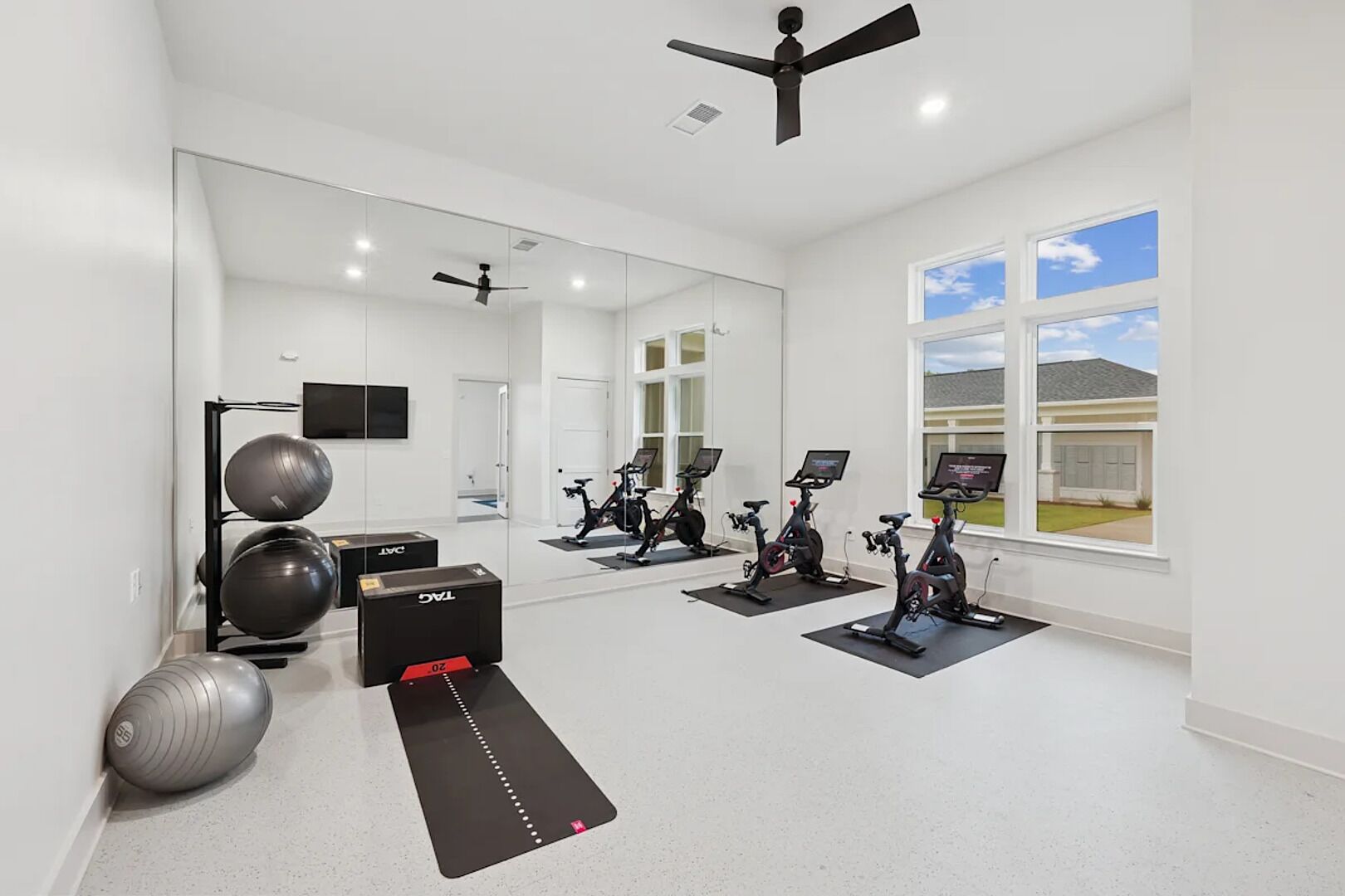 A modern gym with exercise bikes, a treadmill, and weight equipment.