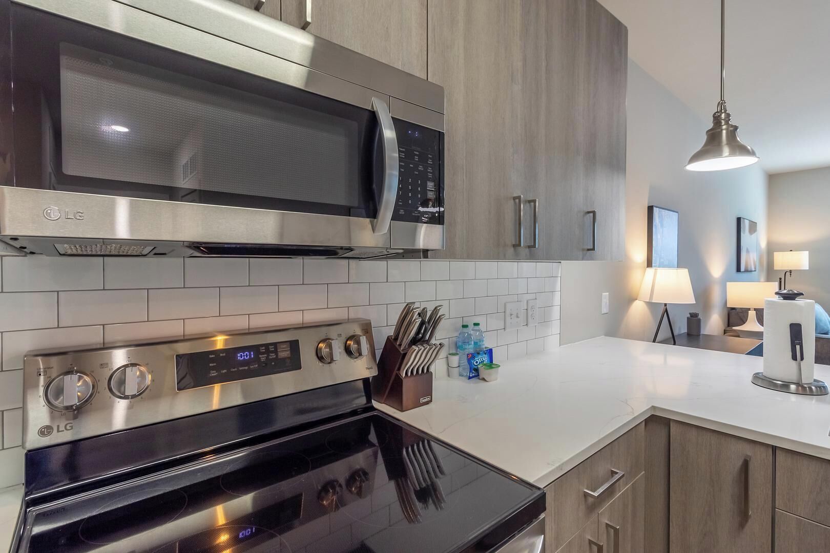 A modern kitchen with stainless steel appliances, including a microwave and oven, and wooden cabinetry.