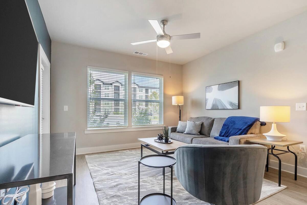 A modern living room with a sofa, two side tables, a coffee table, and a ceiling fan.