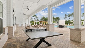 An outdoor patio area with a ping pong table, lounge chairs, and a pool. - Landing Furnished Apartments Near Point Washington State Forest (Santa Rosa Beach)