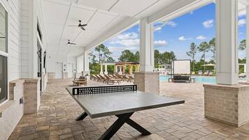 Ein Außenbereich mit Terrasse, einem Tischtennis-Tisch, Liegestühlen und einem Pool.