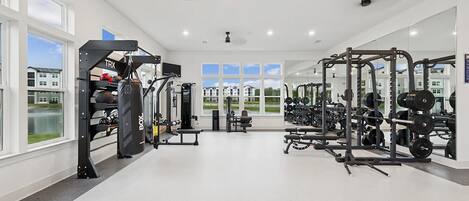 A spacious gym with various exercise equipment, large windows, and a view of the outside.