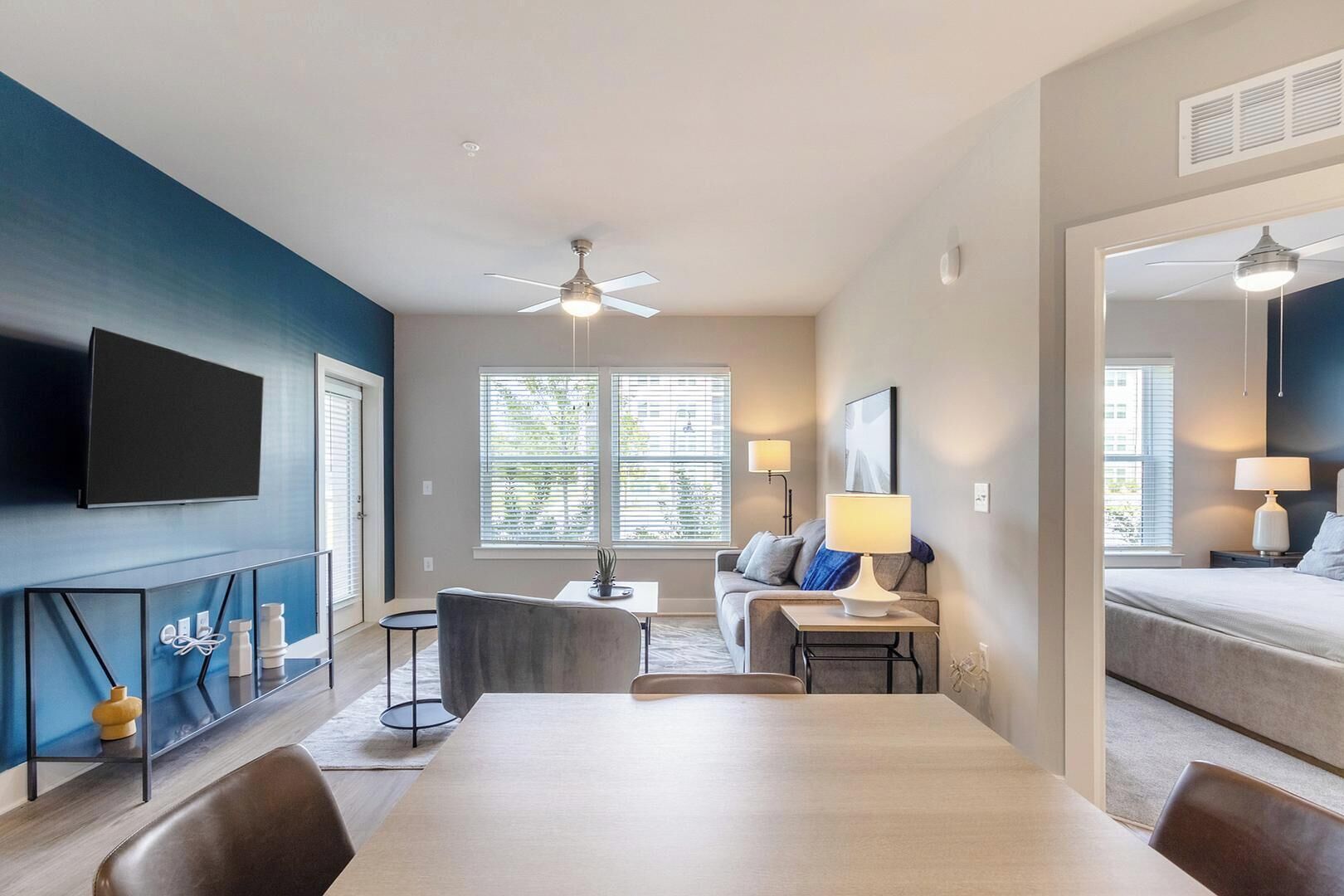 A modern living room with a flat-screen TV, a dining table, and a sofa.