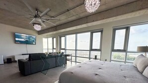 Une chambre moderne avec un grand lit, un bureau, un canapé et un ventilateur de plafond.