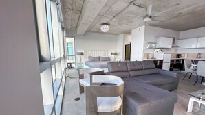 Un salon moderne avec un canapé d’angle, une table basse ronde en bois et un coin repas doté d’une table en verre.
