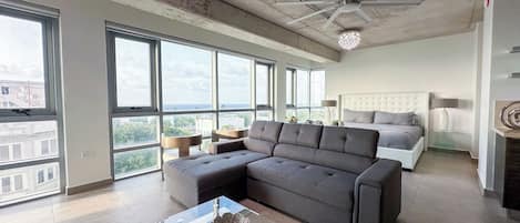 A modern living room with a sectional sofa, a glass coffee table, and a ceiling fan.