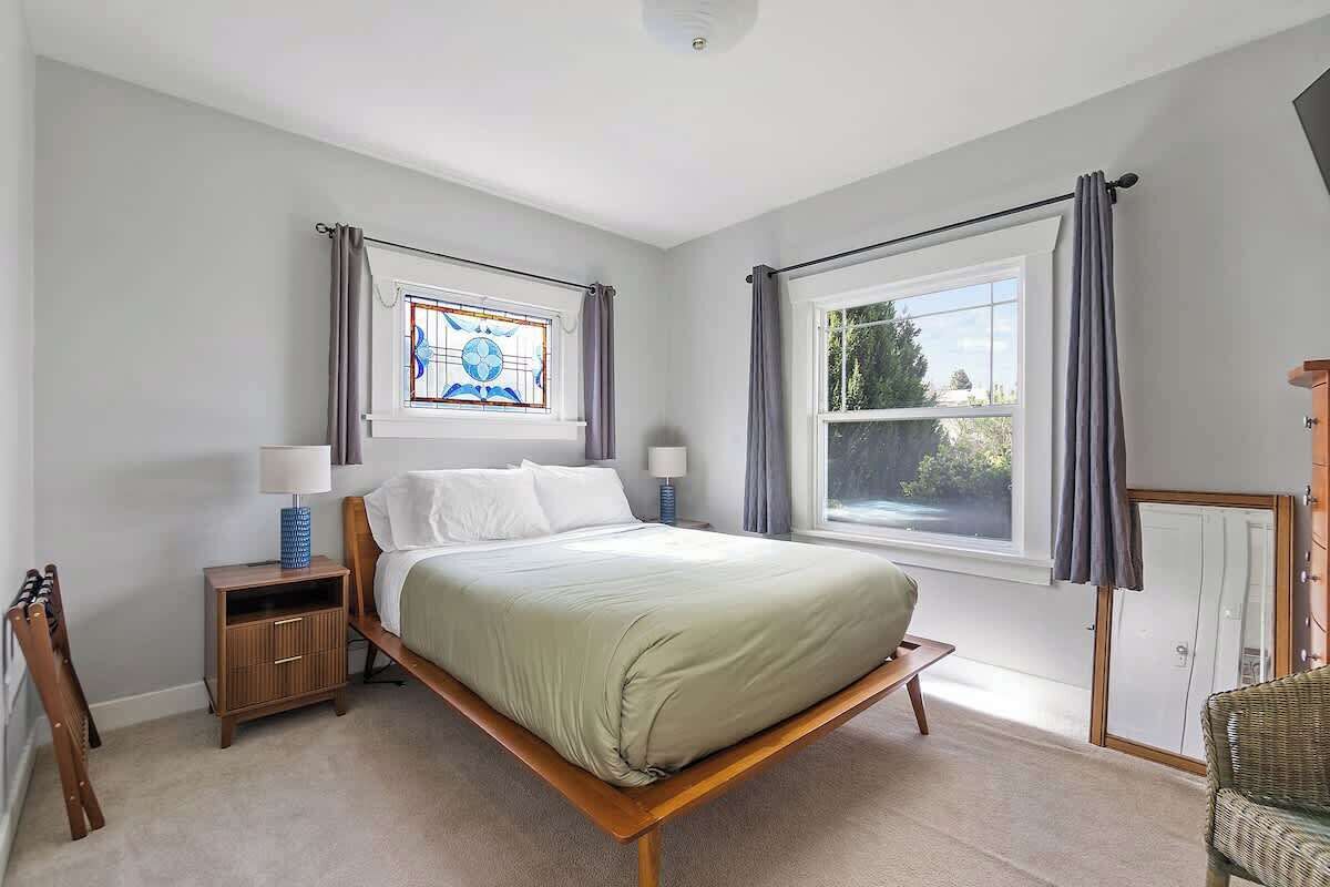 Une chambre à coucher avec un lit, des tables de chevet, une fenêtre et une chaise.