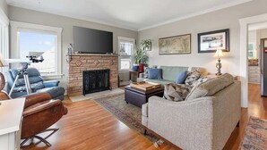 A living room with a fireplace, a television, a sofa, and a coffee table. - Historic PNW Bungalow - Sunset & Water View (Everett)