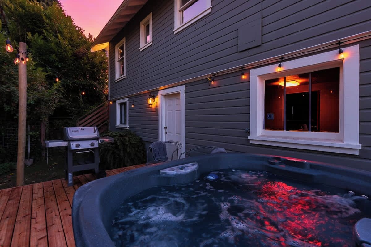 Un bain à remous sur une terrasse en bois, avec une maison en arrière-plan.