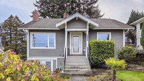 A two-story house with a front porch, a small garden with a palm tree, and a mailbox. - Historic PNW Bungalow - Sunset & Water View (Everett)