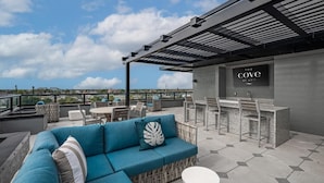 Een terras op het dak met een blauwe bank, een eethoek en een bar.