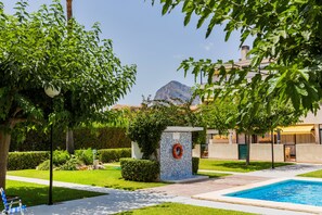 A swimming pool area with a lifebuoy, a bench, and a view of a mountain. - Santa Barbara Montgo Apartment Javea Montañar (Javea / Xàbia)