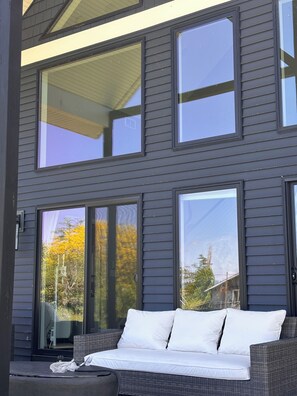 A modern two-story building with large windows and a balcony with a wicker sofa. - Wonderful 4-bedroom house with AC in peaceful Broadalbin (Broadalbin)