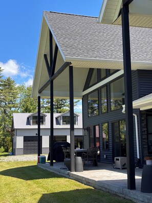 Ein modernes Haus mit überdachter Terrasse, Garage und Rasenfläche.