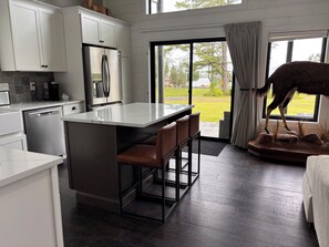 A modern kitchen with white cabinets, a stainless steel refrigerator, and a bar area with stools. - Wonderful 4-bedroom house with AC in peaceful Broadalbin (Broadalbin)
