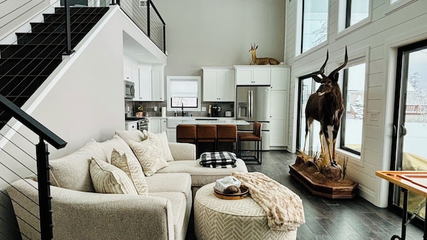 Een moderne woonkamer met een bank, een poef en een opgehangen dierenhoofd.