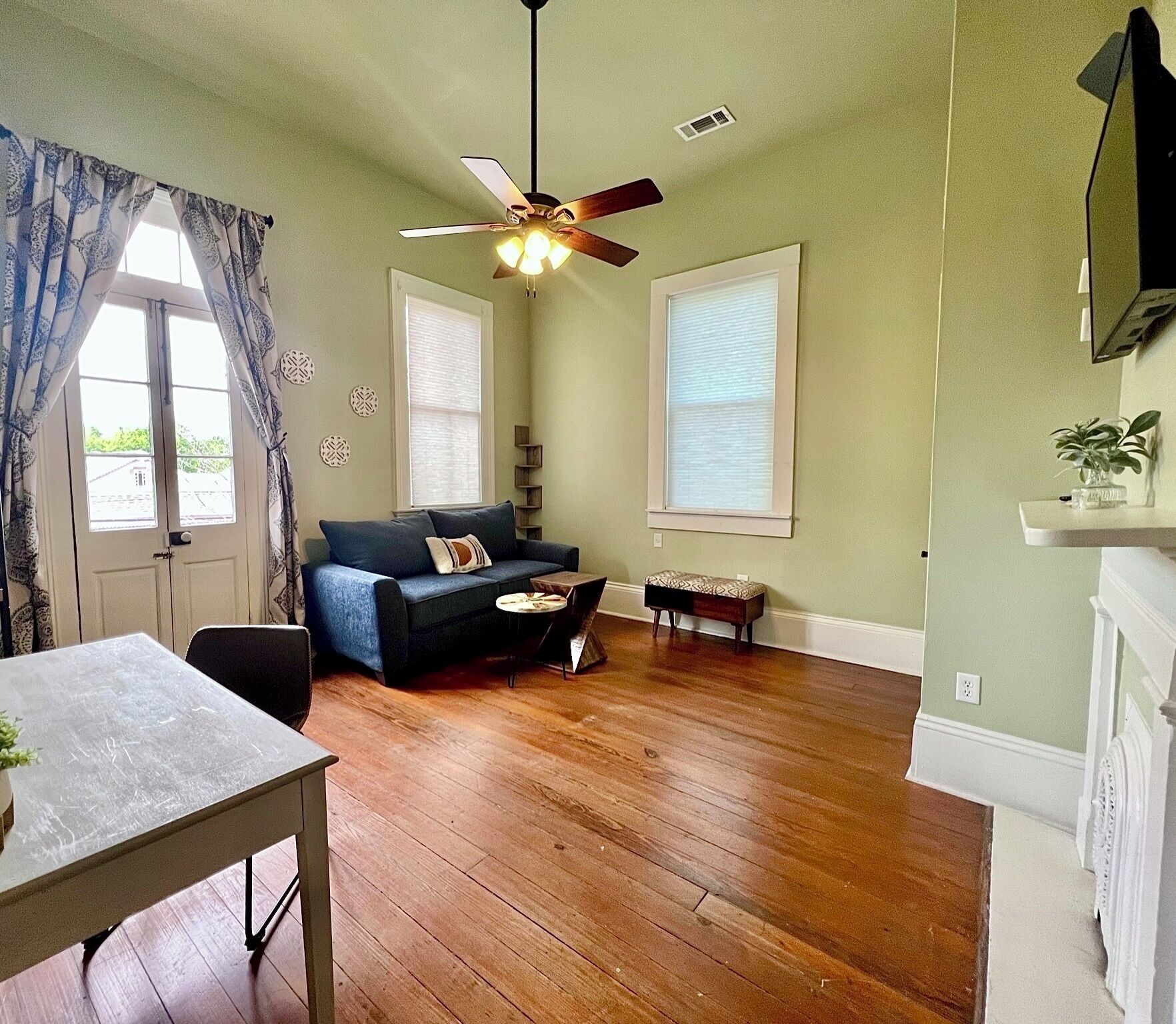 A living room with a ceiling fan, a sofa, a coffee table, and a dining table.